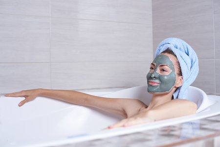 Portrait of a woman in facial alginate mask lying in the retro bath in the bathroom.の写真素材