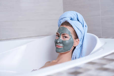 Portrait of a woman in facial alginate mask lying in the retro bath in the bathroom.の写真素材