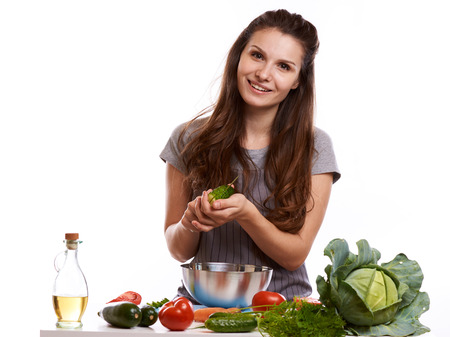 happy adult woman with various fresh vegetables on kitchen table looking at camera.の写真素材
