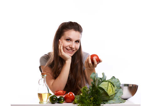 happy adult woman with various fresh vegetables on kitchen table looking at camera.の写真素材