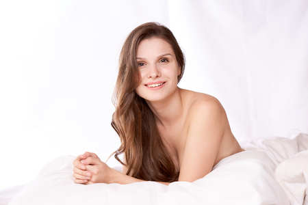 brunette woman lying on bed in bedroom.の写真素材