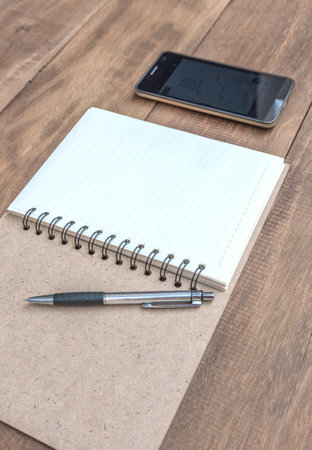 Open a blank notebook , pen and mobile phone on the tableの写真素材