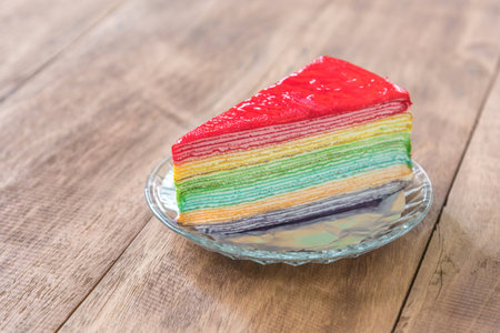 Delicious rainbow cake on plate on wooden tableの写真素材
