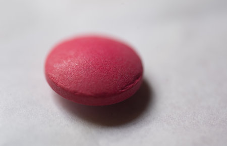 Close-up of a red pill on white background. Focus on foreground.の写真素材