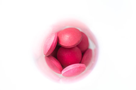 Pink pills on white background. Focus on foreground, soft bokeh.の写真素材