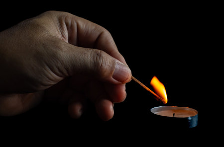 Hand holding a burning match on a black background, close-upの写真素材