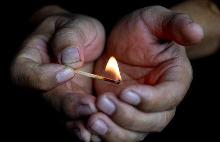 Burning match in the hands of a man on a black backgroundの写真素材