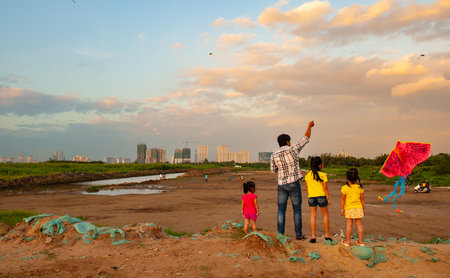 Children playing with kite on the ground in the park at sunset.の写真素材