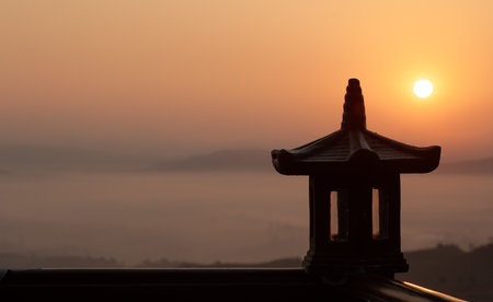 An ancient temple at dawn in front of the mountains and forests covered in clouds.の写真素材
