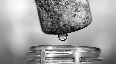 Close up of a water drop falling from a coffee maker in black and white