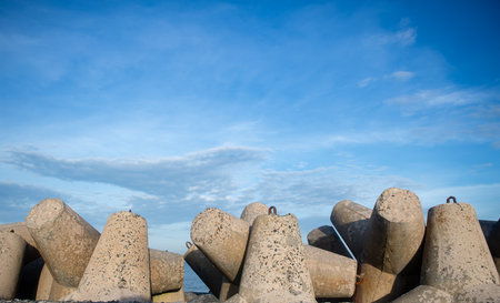 concrete breakwater on the beach with blue sky and white clouds