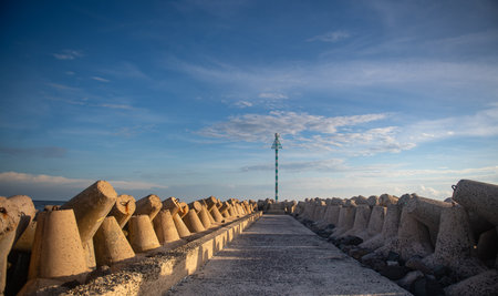 Breakwater on the seashore with a lighthouse in the background