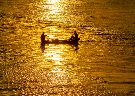 Silhouette of fishermen in the boat on the sea at sunset.の写真素材