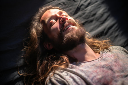 Portrait of a young man with long hair and beard in the rays of sunlightの素材