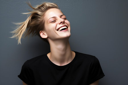 Portrait of a happy young woman laughing against gray wall background.の素材