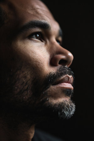 Close-up portrait of a man with a beard on a black backgroundの素材