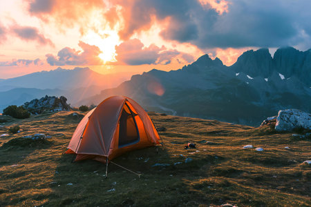 Camping in the mountains. The tent stands on the grass against the backdrop of the sunset.の素材