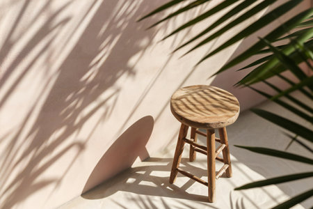 Wooden stool with palm leaves shadow on white wall. Mock upの素材