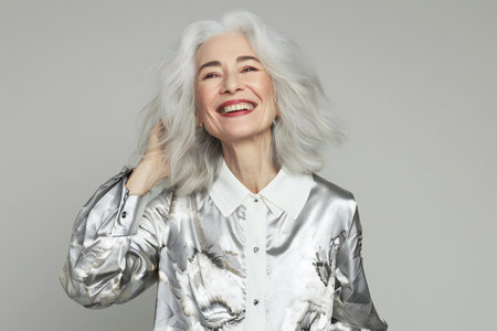 Mature woman with white hair on grey background. Studio shot.の素材