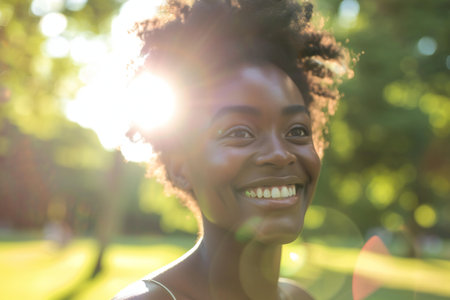 Portrait of smiling african american woman in park at sunny dayの素材