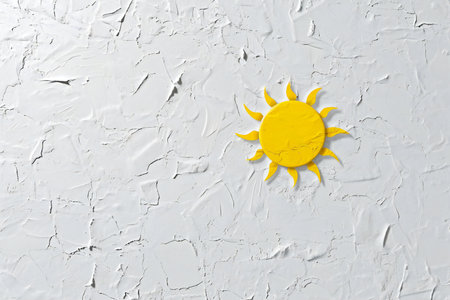 Yellow sun painted on white concrete wall. Minimal summer concept.の素材