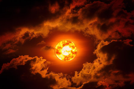 Sunset with clouds in the sky. Orange sun on dark background.の素材