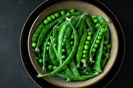 Fresh green peas in a bowl on a black background, top viewの素材