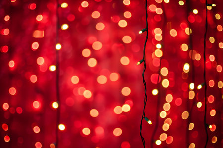 Christmas lights on a red background. Festive background with bokeh defocused lights.の素材
