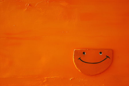 Funny smiley on orange wall background, closeup of photoの素材
