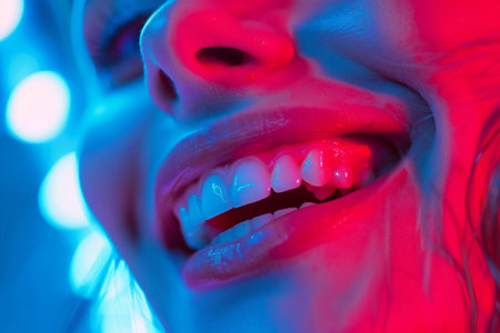 Close-up of beautiful female teeth with red and blue neon lightの素材