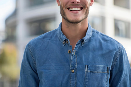 Close-up of smiling young man in jeans shirt on city streetの素材