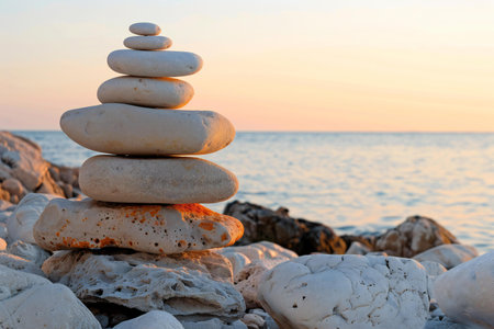 Stacked zen stones on the seashore at sunset.の素材