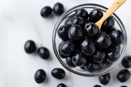 Black olives in glass bowl on white background. Top view.