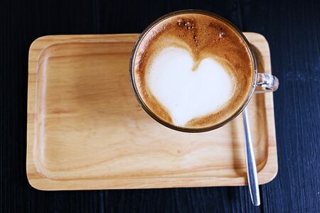 coffee with heart shape foam top view on wooden trayの写真素材