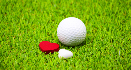 golf ball and heart shape on green grassの写真素材