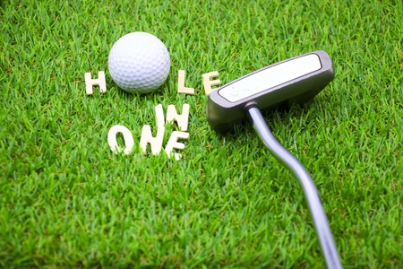 Hole in on wording and golf ball and putter are on green courseの写真素材