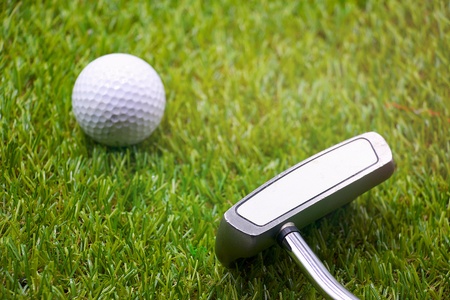 Golf ball and putter are on green course with morning lightの写真素材