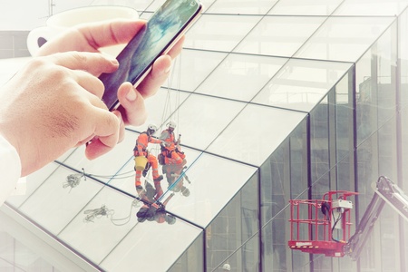 Hand is using mobile with constructional worker backgroundの写真素材