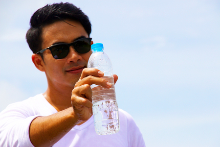 One Asian man is holding a bottle of  drinking water or potable water or improved drinking water, is water that is safe to drink or to use for food preparation, without risk of health problemsの写真素材
