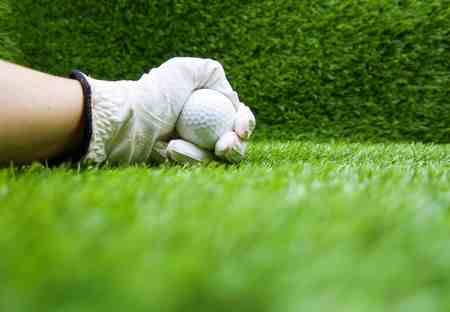 Hand is holding golf ball is on green grasの写真素材