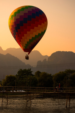 Colorful balloon is over Song river in Vang Vieng with sunset view behind the mountain.のeditorial素材