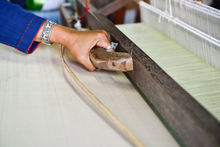 Thai woman hand weaving silk being used to make cloth