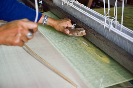 Thai woman hand weaving silk being used to make clothの写真素材