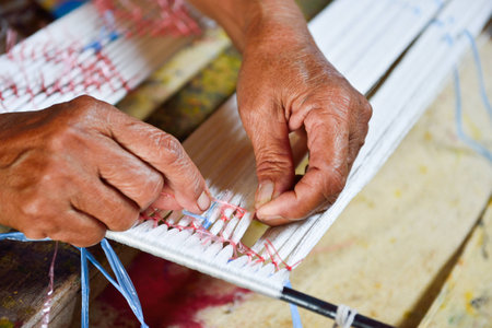 Thai woman hand weaving silk being used to make clothの写真素材