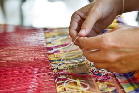 Hand of a woman weaving traditional silk fabric in Thailand