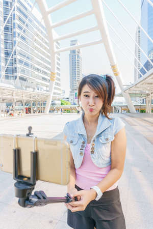 Pretty girl taking a selfie in city with smartphoneの写真素材