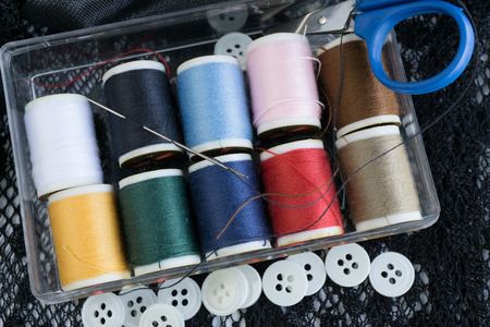 colorful thread in plastic box, scissors and buttons for sewing and tailoring