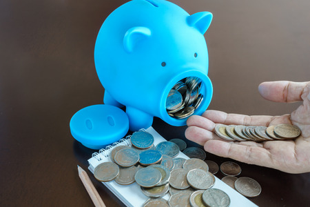 Money in Man hand from saving in Piggy Bankの写真素材
