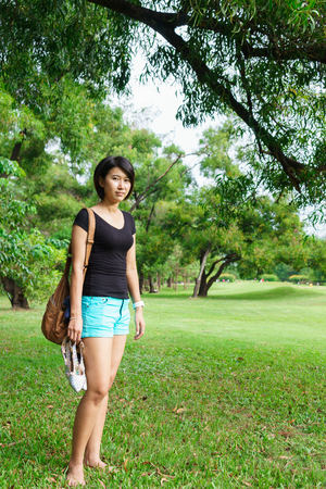 Asian girl take off her shoes standing on the grass in park, young woman relax in green parkの写真素材