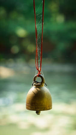 Buddhist bell is hanging with red rope in blur backgroundの写真素材